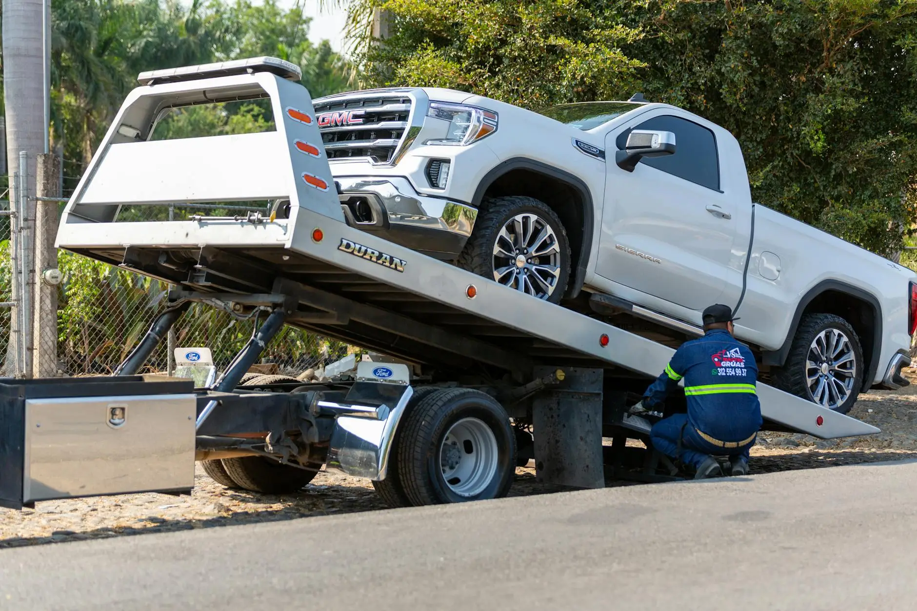 A professional tow truck operator securing a passenger vehicle onto a flatbed tow truck in Rayville, LA.